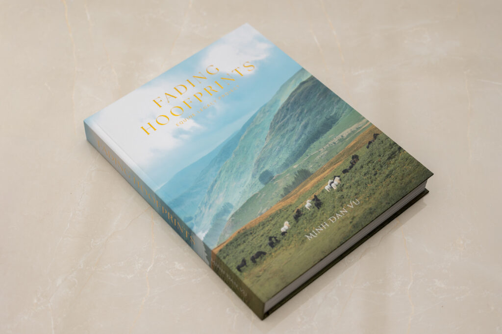 The hardcover coffee table book Fading Hoofprints by the Equine Legacy Project resting on a marble surface